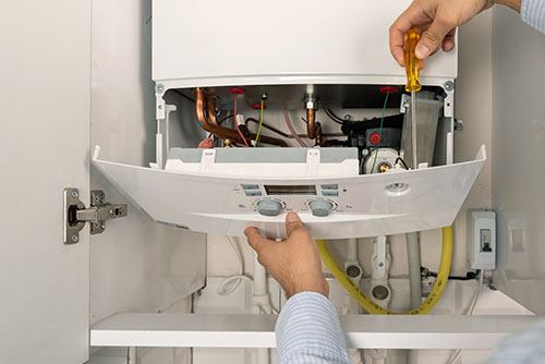 Heating technician repairing a residential boiler in Riverside