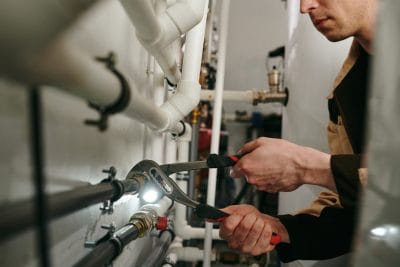 Technician inspecting commercial plumbing pipes in Riverside