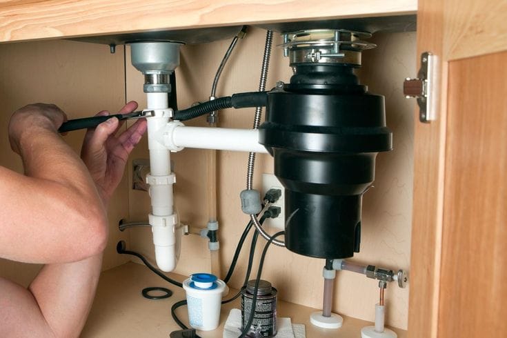 Plumber repairing a garbage disposal in Riverside