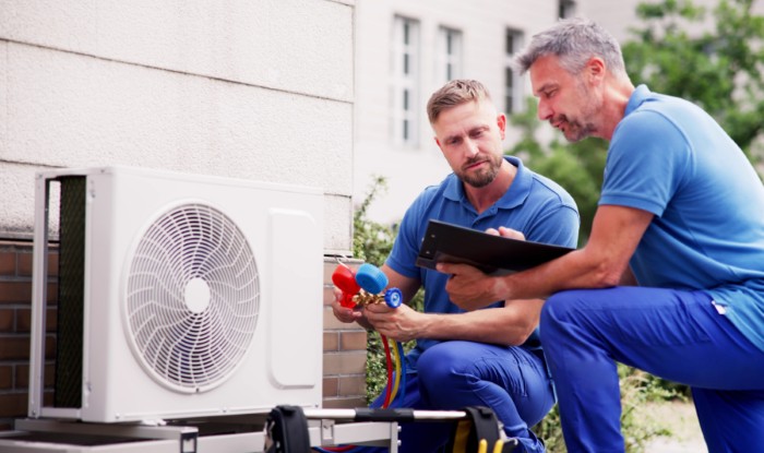 HVAC technicians installing an outdoor air conditioning unit in Riverside