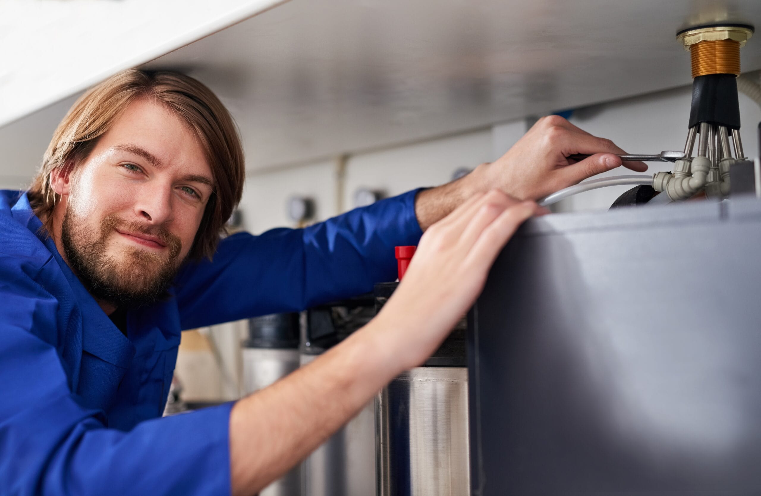 Technician servicing a residential water heater tank in Riverside